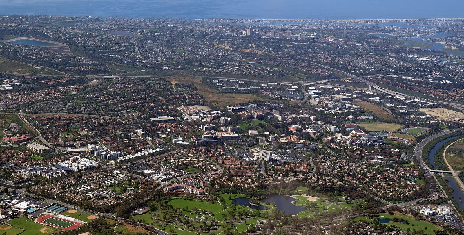 UC Irvine 校园与尔湾南部街区航拍资料图（远处为 Newport Beach）